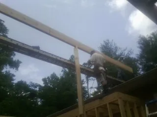 Carpenter setting a ridge beam over a new addition frame — Ice Dam Removal by Roofing Brothers in Nelsonia