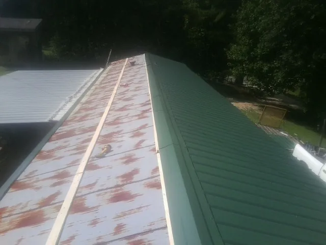 Old rusted panels beside newly installed green metal roofing — Wind Damage Roof Repair by Roofing Brothers in Nelsonia