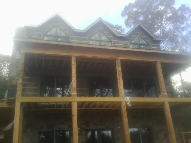 Dormers and porch framing on a large log home under construction — Roof Coating work by our crew in Nelsonia
