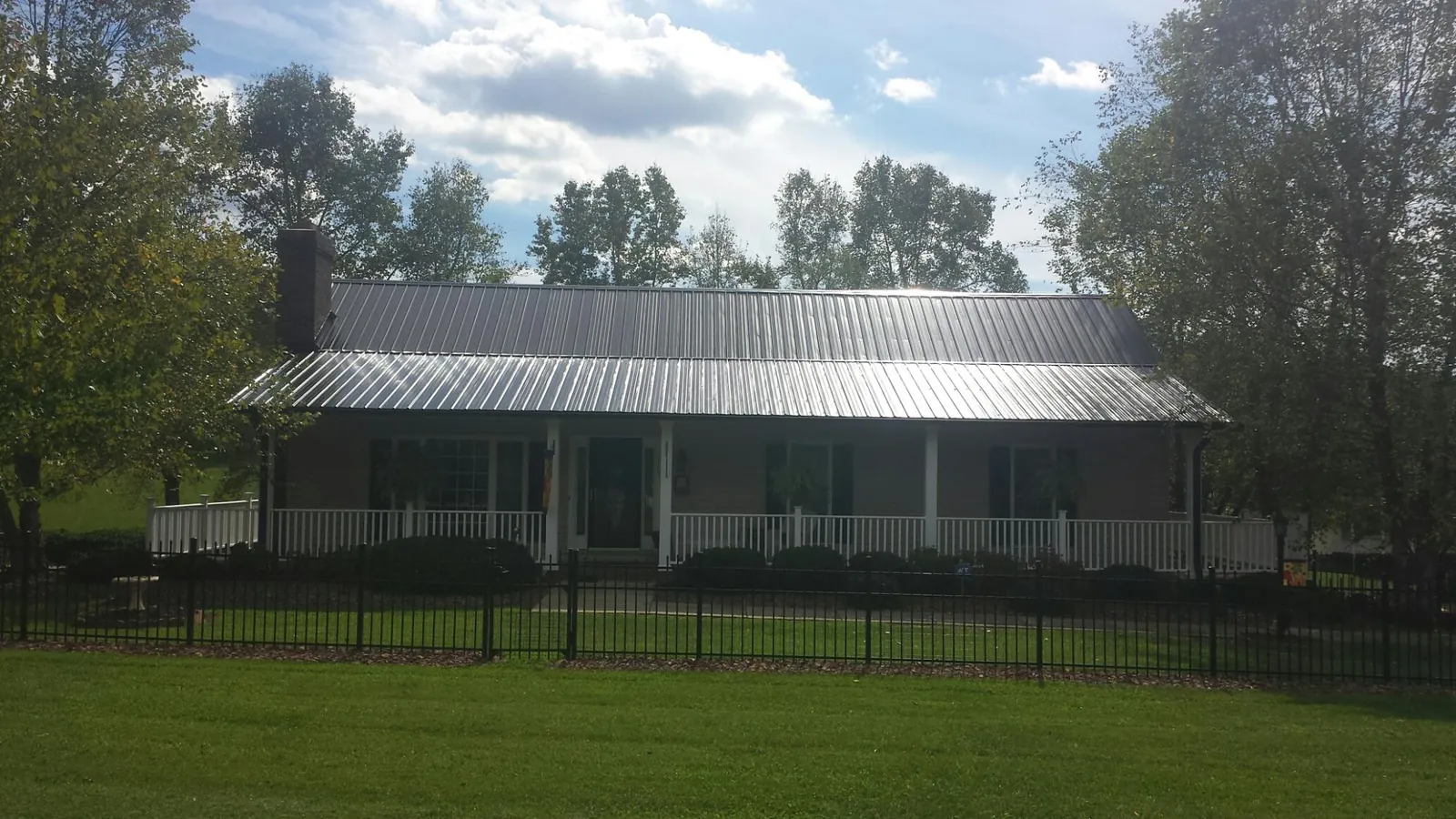 Gray metal roof on a brick ranch with a full width front porch — Gutter Guard Installation work by our crew in Nelsonia