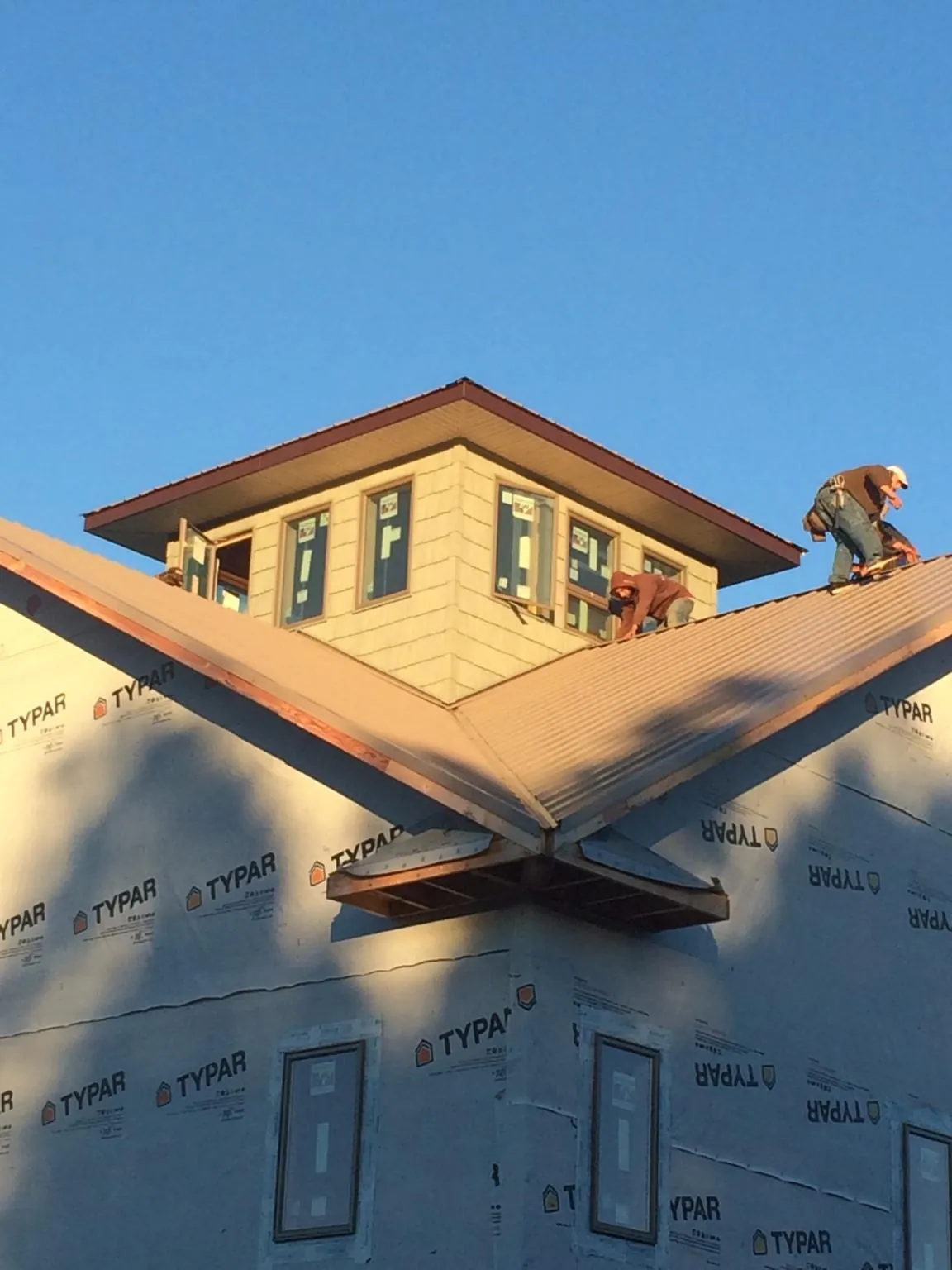 Roofers working around a rooftop cupola on a new metal roof at sunset — Roof Waterproofing in Nelsonia by Roofing Brothers